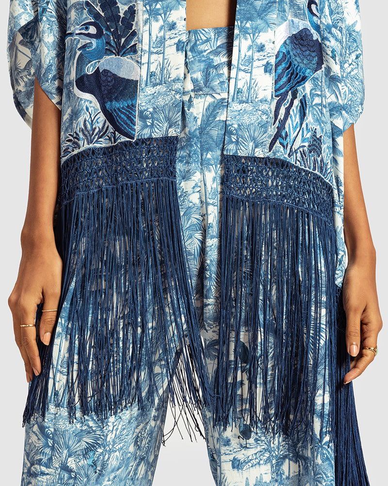 Blue Gara Embroidered Tropical Print ShrugProduct DescriptionMade from silk satin, this statement shrug is enveloped in a blend of tropical print and tonal Gara embroidery. Also features a generous silk frinShrugsBlue Gara Embroidered Tropical Print Shrug