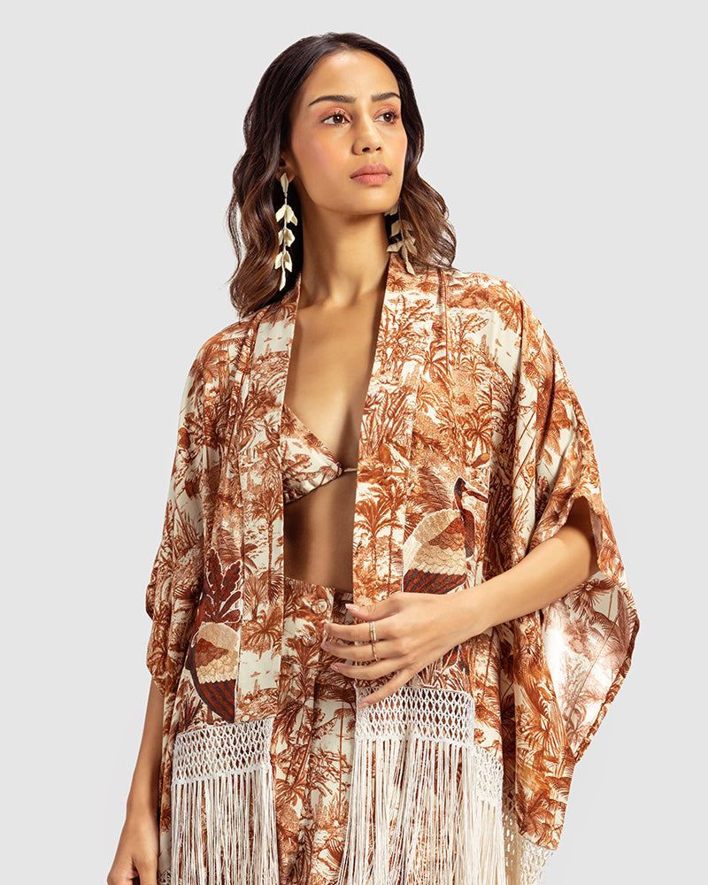 Brown Gara Embroidered Tropical Print ShrugProduct DescriptionMade from silk satin, this statement shrug is enveloped in a blend of tropical print and tonal Gara embroidery. Also features a generous silk frinShrugsBrown Gara Embroidered Tropical Print Shrug