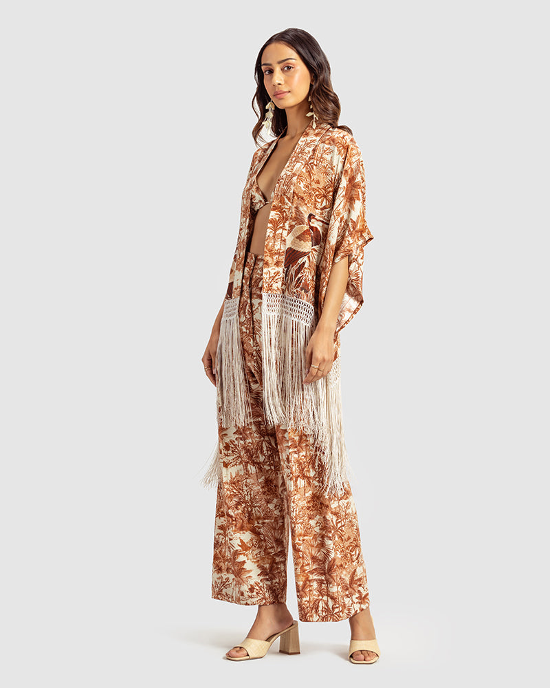 Brown Gara Embroidered Tropical Print ShrugProduct DescriptionMade from silk satin, this statement shrug is enveloped in a blend of tropical print and tonal Gara embroidery. Also features a generous silk frinShrugsBrown Gara Embroidered Tropical Print Shrug