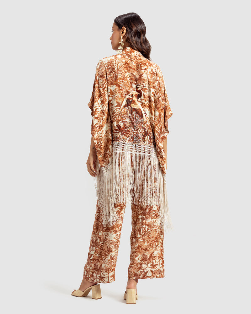 Brown Gara Embroidered Tropical Print ShrugProduct DescriptionMade from silk satin, this statement shrug is enveloped in a blend of tropical print and tonal Gara embroidery. Also features a generous silk frinShrugsBrown Gara Embroidered Tropical Print Shrug