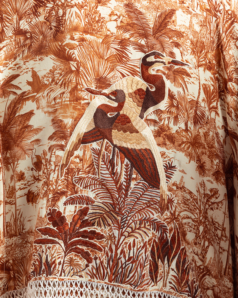 Brown Gara Embroidered Tropical Print ShrugProduct DescriptionMade from silk satin, this statement shrug is enveloped in a blend of tropical print and tonal Gara embroidery. Also features a generous silk frinShrugsBrown Gara Embroidered Tropical Print Shrug