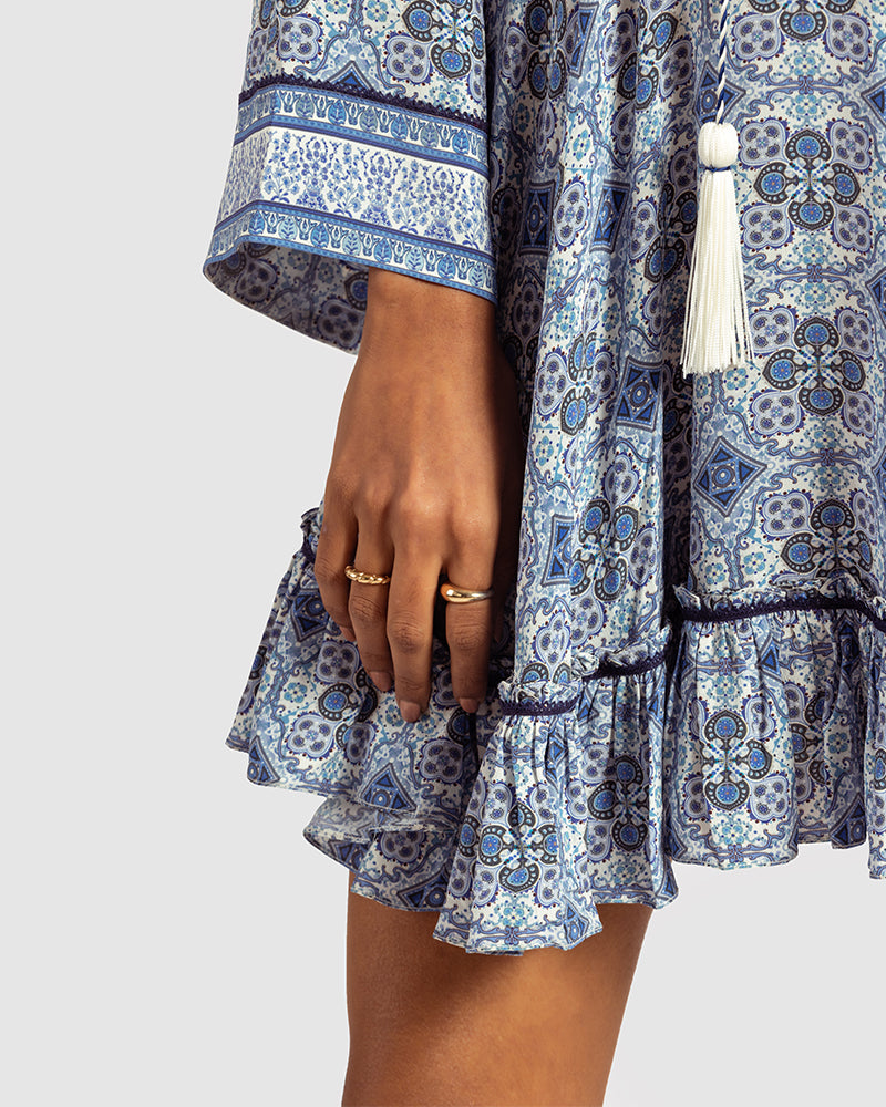Blue Marissa Print Ruffled Silk DressProduct DescriptionThis print patchwork ruffled dress is a mix of fit and flare, making it a perfect summer dress. It features a V-shaped neckline, a tasselled drawsDressesBlue Marissa Print Ruffled Silk Dress