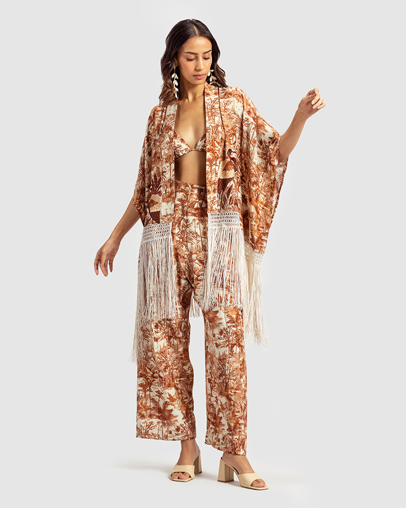 Brown Gara Embroidered Tropical Print ShrugProduct DescriptionMade from silk satin, this statement shrug is enveloped in a blend of tropical print and tonal Gara embroidery. Also features a generous silk frinShrugsBrown Gara Embroidered Tropical Print Shrug